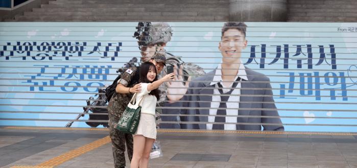 Soldiers take pictures in front of the outdoor adv